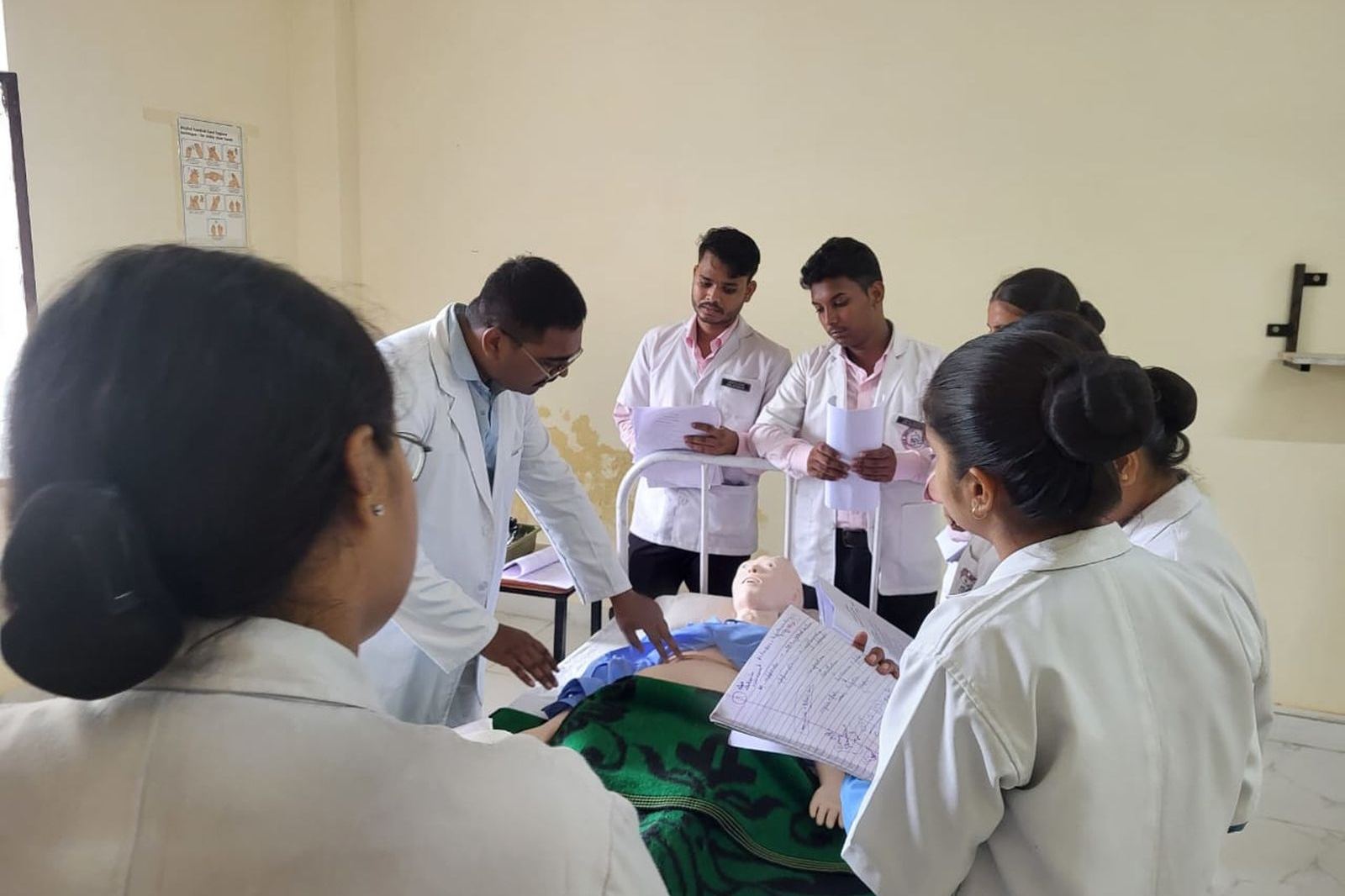 Medical trainees in white coats gathered around a hands-on training session